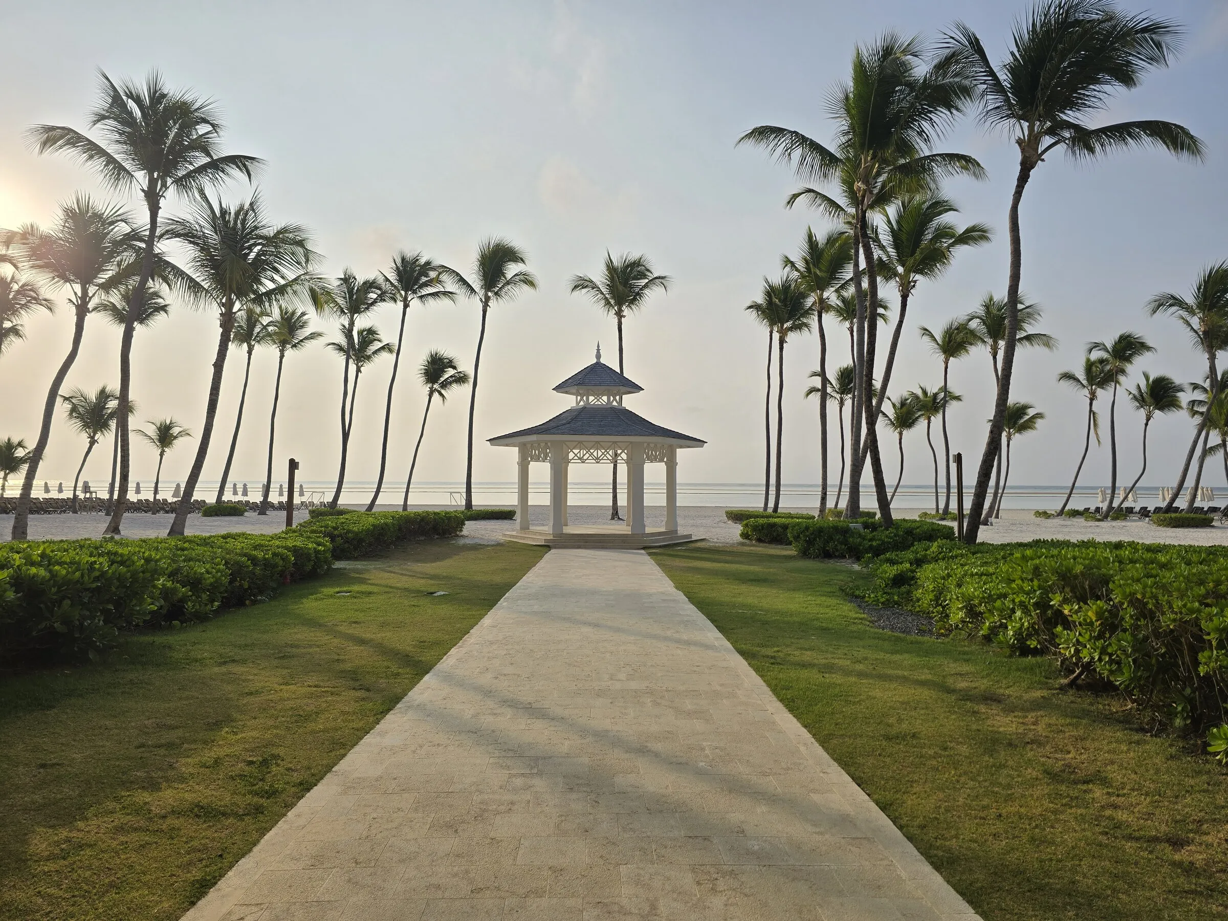 A palm-lined path leading toward a quiet ocean pavilion in Punta Cana